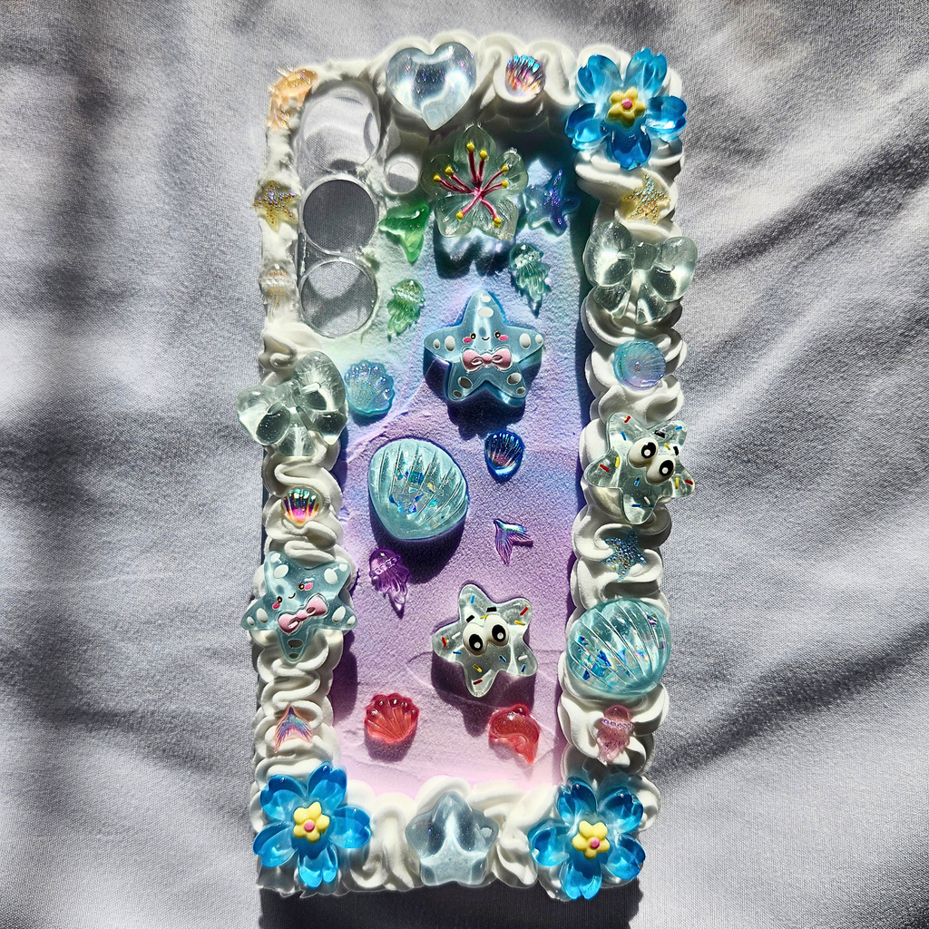 Decorative phone case with colorful crystals and starfish on a gray fabric background