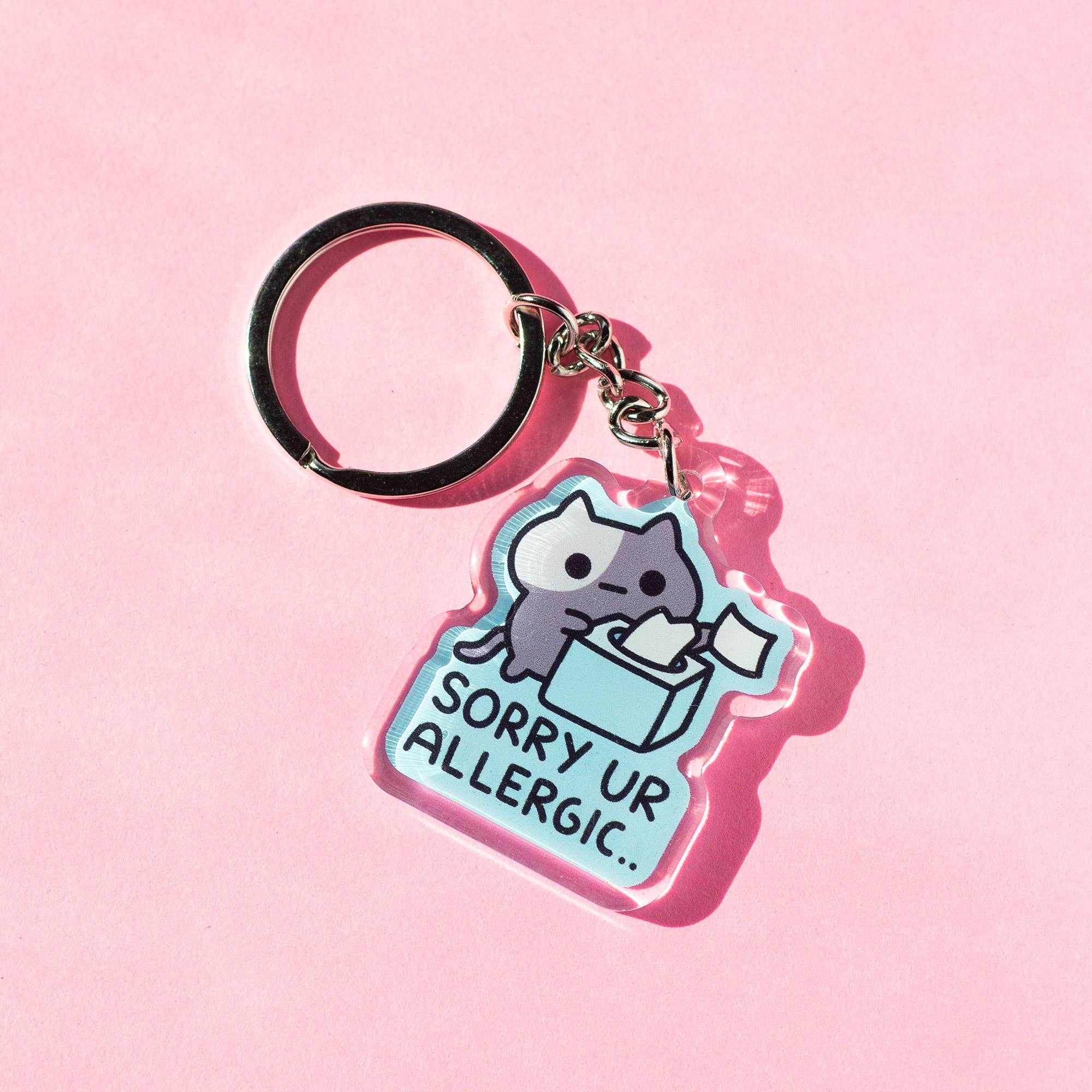 Keychain with a cat design and text 'Sorry Ur Allergic' on a pink background