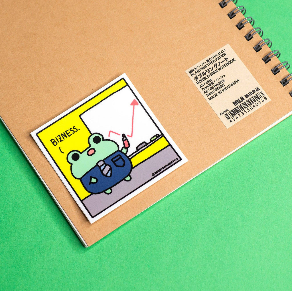 Notebook with a sticker featuring a cartoon frog and text on a green background