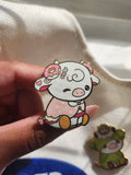 Cartoon pig pin held by a hand with another pin in the background
