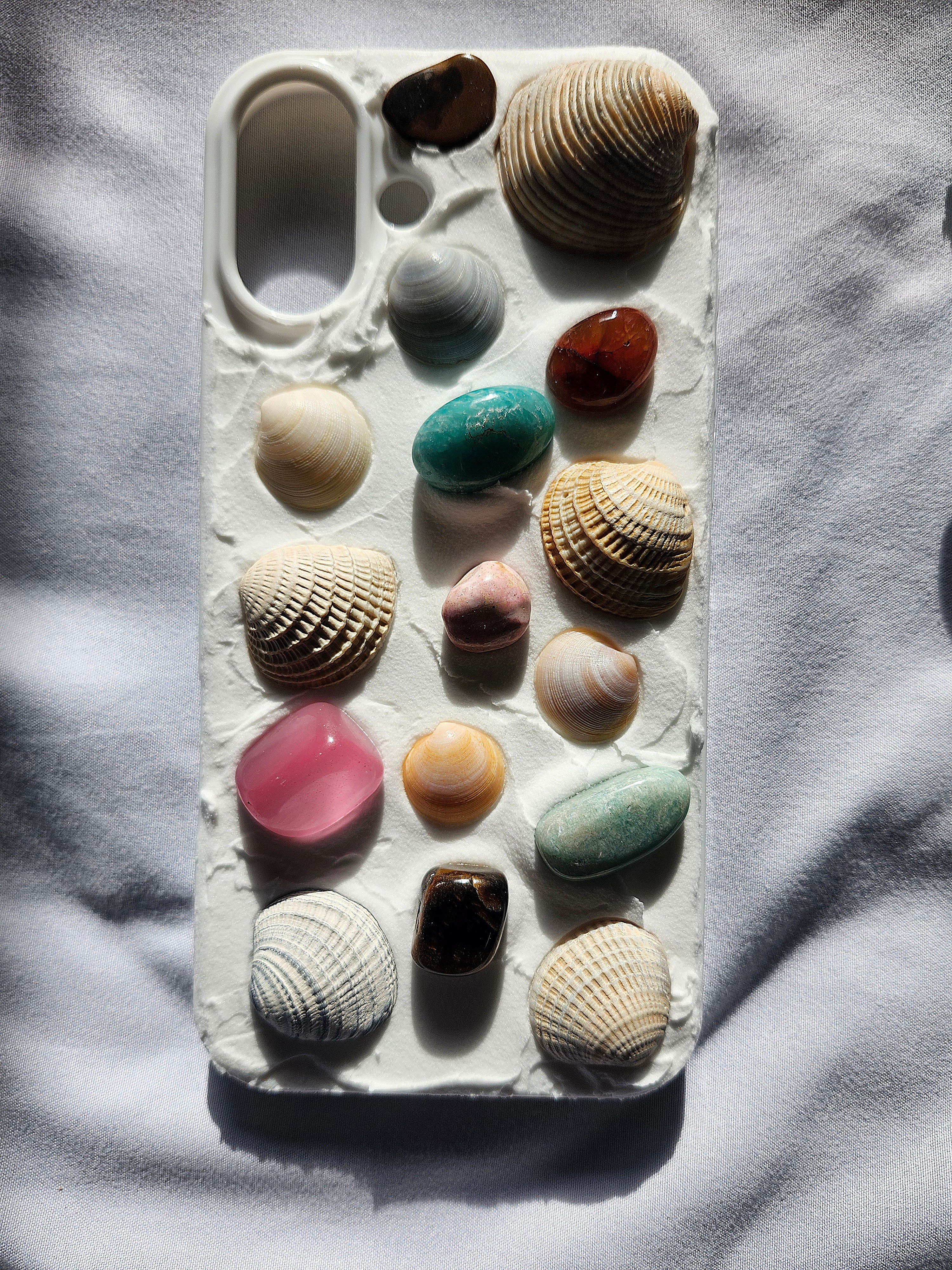 Phone case with various seashells on a textured surface