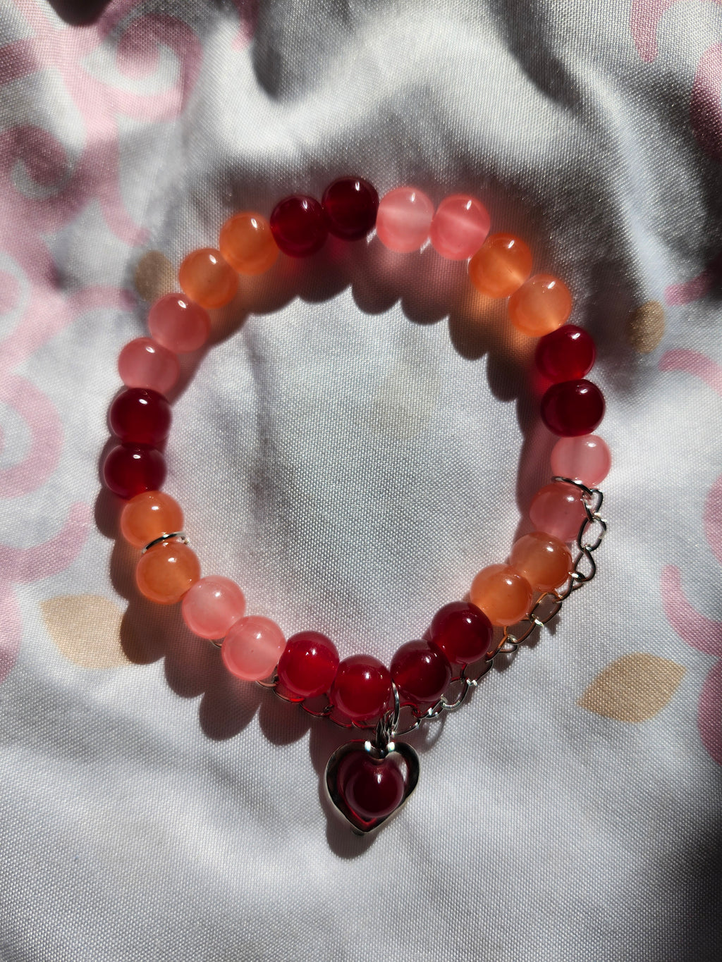 Bracelet with red and pink beads on a patterned fabric background