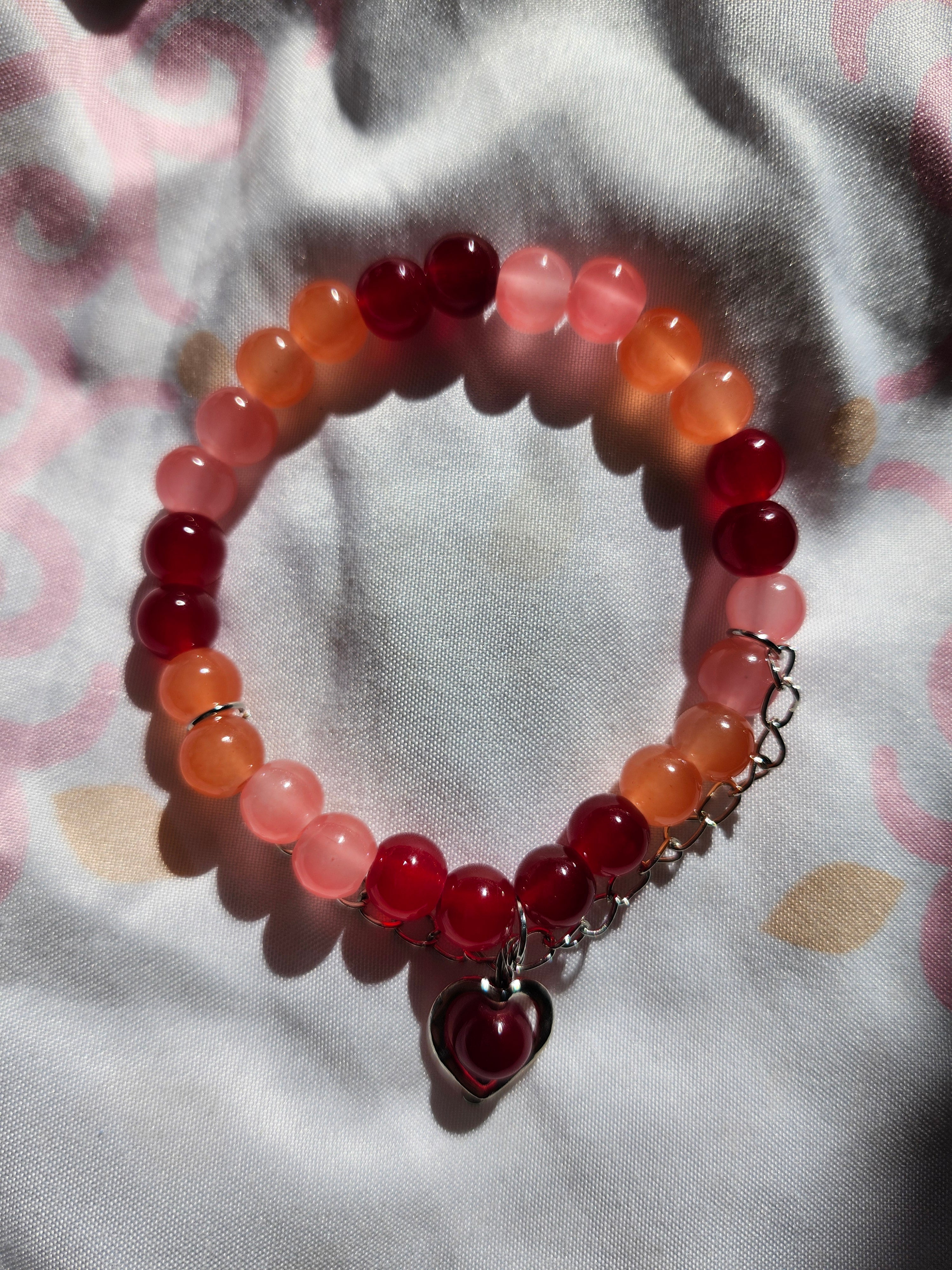 Bracelet with red and pink beads on a patterned fabric background