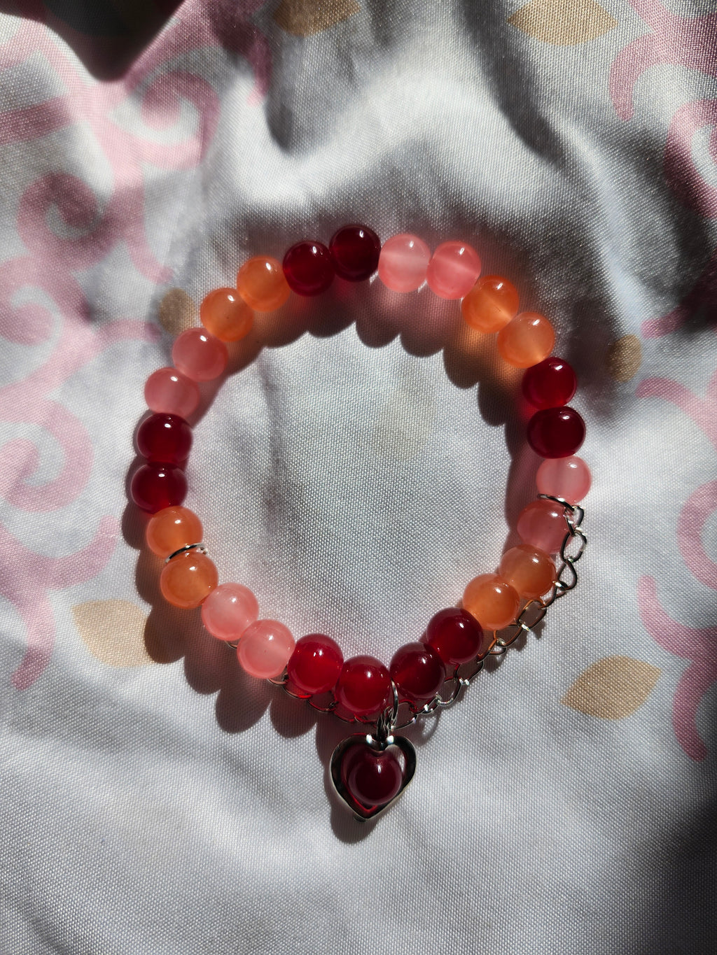 Beaded bracelet with red and pink beads on a patterned fabric background
