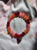 Beaded bracelet with red and pink beads on a patterned fabric background