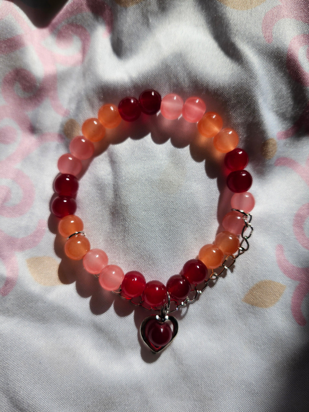 Beaded bracelet with red and pink beads on a patterned fabric background