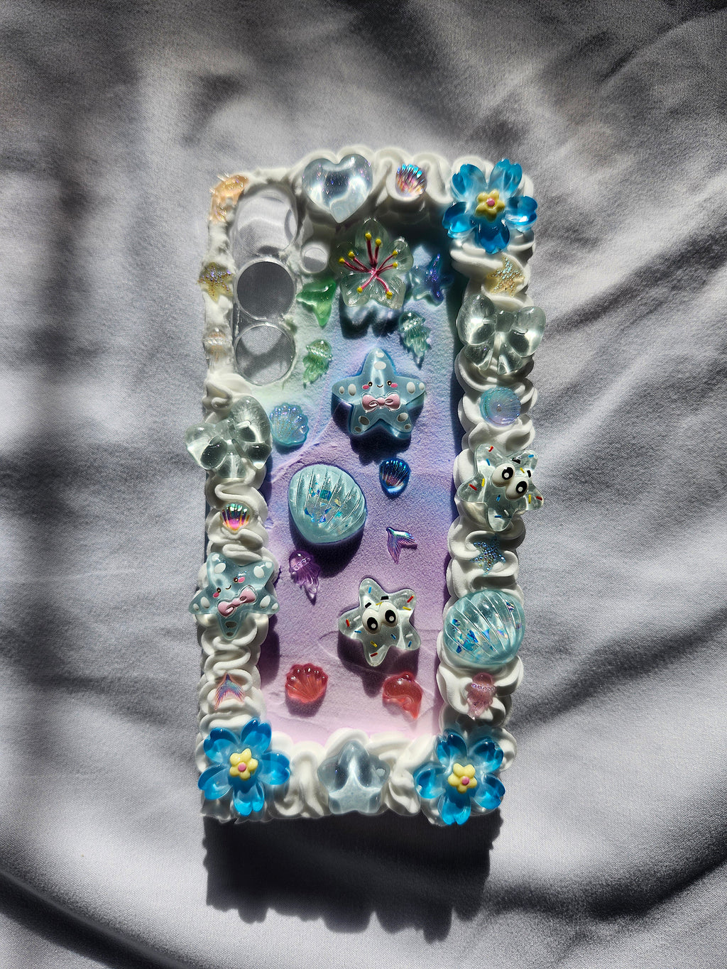 Decorative phone case with colorful gemstones and floral designs on a textured surface.